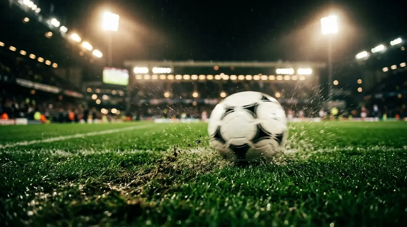 Detail fotbalového míče v pohybu na trávníku při večerním osvětlení stadionu